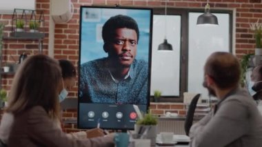 Çeşitli iş arkadaşları çevrimiçi video konferansında adamla konuşuyor.