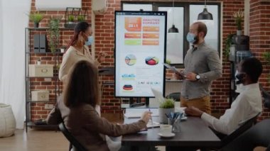 Çok ırklı iş arkadaşlarından oluşan bir ekip ofiste sunum yapıyor.