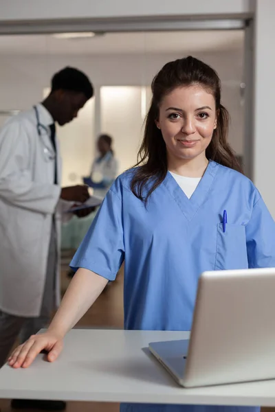 Retrato de la terapeuta especialista sonriente asistente mujer de pie en el escritorio en la sala de hospital — Foto de Stock