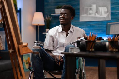 Tekerlekli sandalyedeki Afrikalı Amerikalı ressam defterine çizim yapıyor.