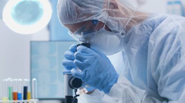 Kimyager tıbbi mikroskobu inceliyor DNA örneğini analiz ediyor.