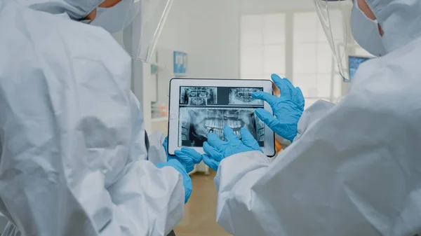 Врачи-стоматологи изучают рентген зубов на экране планшета — стоковое фото
