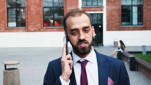 Akıllı telefonu elinde tutan bir işadamının portresi şirket stratejisini açıklayan bir yöneticiyle konuşuyor. — Stok fotoğraf