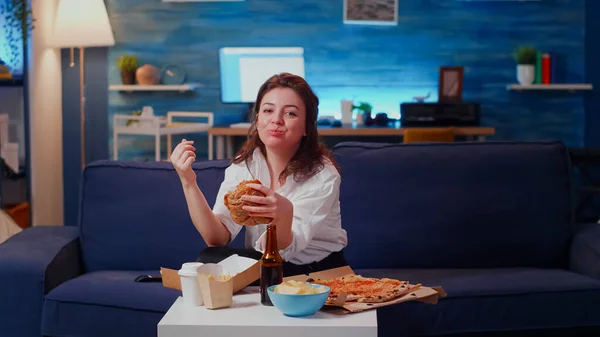 Young woman eating hamburger and fries laughing — Stock Photo, Image