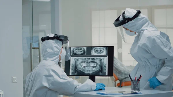 Odontologia médica com ternos ppe usando tecnologia moderna — Fotografia de Stock