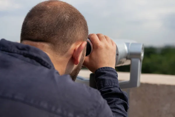 Крупный план кавказского мужчины, смотрящего в бинокль туристический телескоп — стоковое фото
