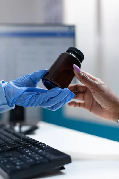 Closeup of doctor hand giving pills bottle to african american sick patient — Stock Photo, Image