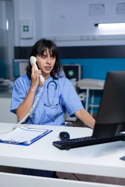 Medical assistant talking on landline phone for healthcare — Stock Photo, Image