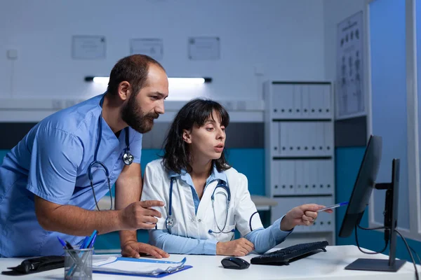 Médico y enfermera apuntando a la computadora para el chequeo — Foto de Stock