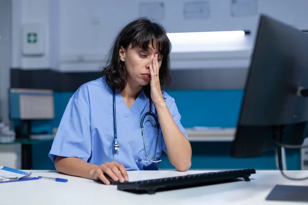 Medical assistant falling asleep while using computer and keyboard — Stock Photo, Image