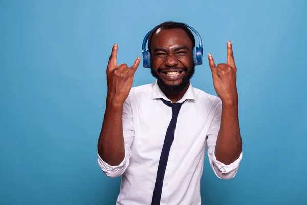 Sonriente hombre lleno de energía haciendo rock and roll signo de la mano mientras escucha música —  Fotos de Stock