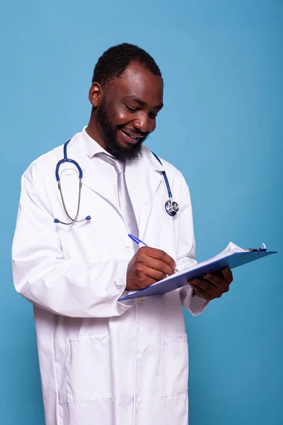 Porträtt av leende läkare tittar ner på Urklipp med patientjournaler — Stockfoto