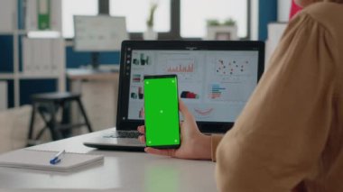 Dikey olarak elinde yeşil ekranlı akıllı telefonu tutan kadına yaklaş