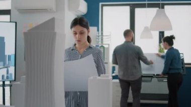 Yapı modelini tasarlamak için planlar üzerinde çalışan kadın mimarın portresi