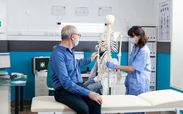 Paciente y enfermera con mascarillas en los huesos de la columna vertebral —  Fotos de Stock