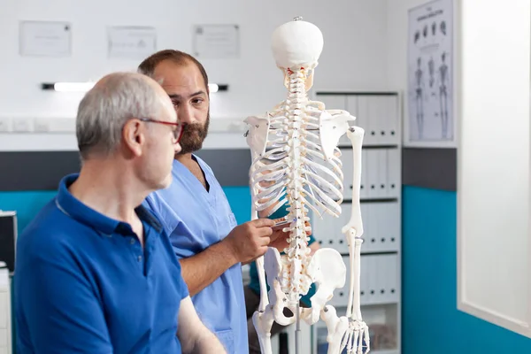 Orthopédiste expliquant la moelle épinière sur le squelette humain — Photo