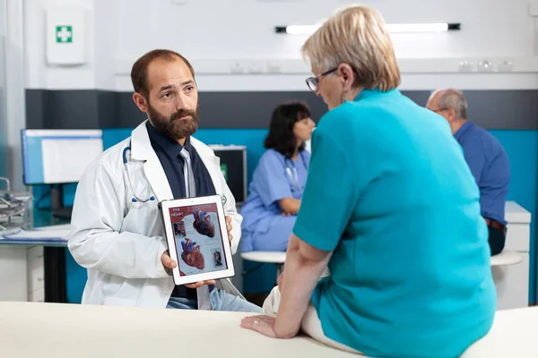 Medical specialist explaining cardiology figure to elder patient — Stock Photo, Image