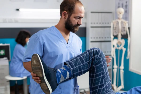 은퇴 한 환자의 다리를 뻗어 생리 치료를 받고 있는 척주 지압 요법사 — 스톡 사진