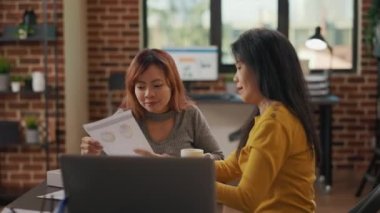Asyalı kadınlar evrak işlerinin satış istatistiklerini inceliyor.