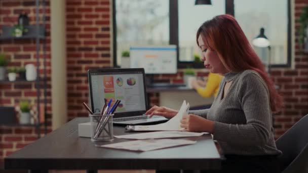 Kantoormedewerker die documenten en laptop gebruikt om leiderschapspresentatie te plannen — Stockvideo