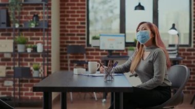 Yüzü maskeli Asyalı bir çalışan adayla iş görüşmesine katılıyor