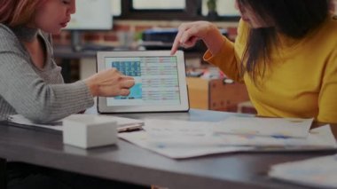 Tabletteki borsa istatistiklerine bakan iş arkadaşları