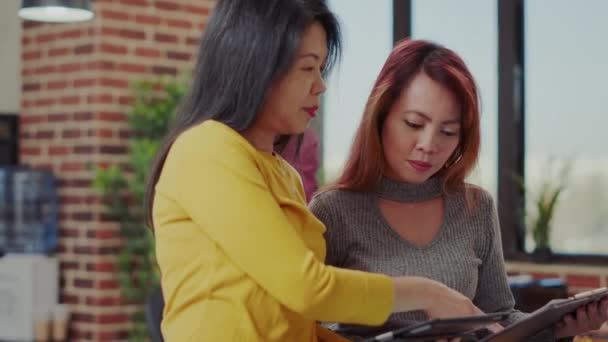 Equipe de mulheres asiáticas analisando tablet e papelada — Vídeo de Stock