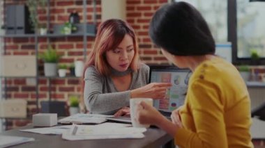 Asyalı kadınlar dizüstü bilgisayardaki iş çizelgelerini inceliyor.