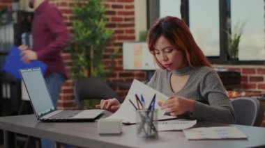 Girişim ofisindeki kağıtların satış istatistiklerini analiz eden iş kadını