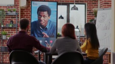 Bir grup iş arkadaşı bir adamla görüntülü görüşme yapıyor.