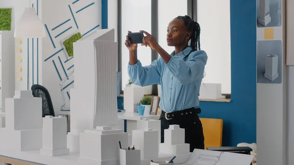 Kvinna ingenjör med hjälp av smartphone för att planera layout av byggnad modell och maquette — Stockfoto