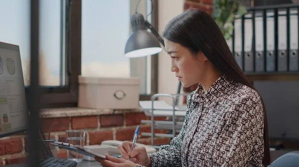 Zakelijke vrouw op zoek naar bestanden op klembord om te werken aan de strategie — Stockfoto