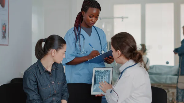 Close up of multi ethnic team explaining x ray diagnosis on tablet — Stockfoto
