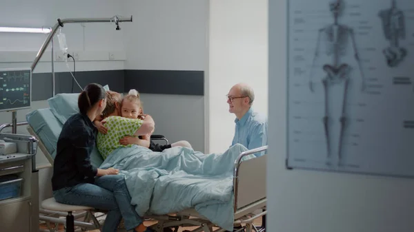 Child hugging sick patient in hospital ward bed at family visit — Stockfoto