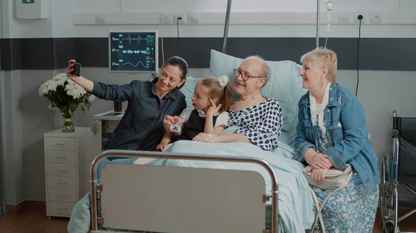 Familie en gepensioneerde man neemt selfie met smartphone op bezoek — Stockfoto