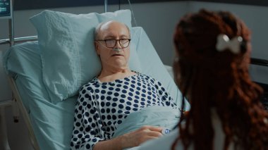 Hasta yaşlı hasta, hastane koğuşunda Afrikalı Amerikalı doktorla konuşuyor.