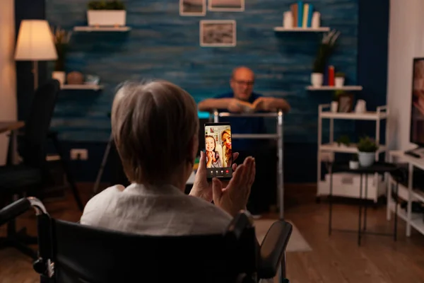 Osoby starsze niepełnosprawne korzystające z połączenia wideo na smartfonie — Zdjęcie stockowe