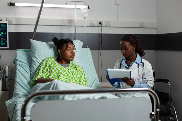 Afro-Amerikaanse arts arts zitten naast zieke patiënt stellen medische vraag — Stockfoto