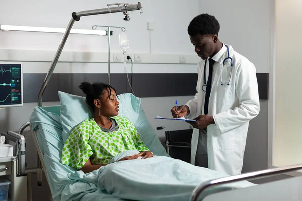 African american practitioner doctor explaining sickness expertise to young woman — Stockfoto