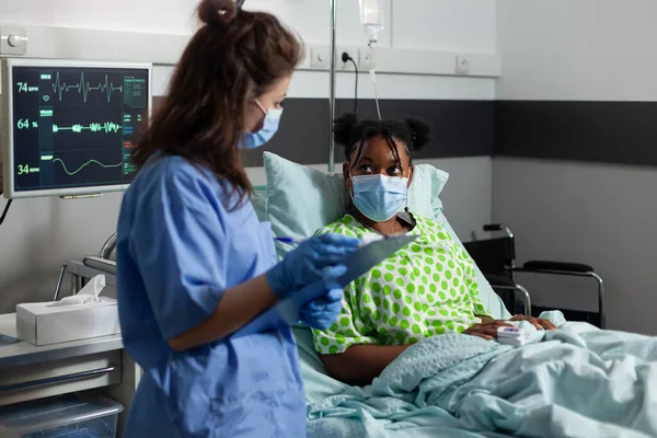 Afro-Amerikaanse jonge patiënt met bescherming gezichtsmasker tegen covid19 liggend in bed — Stockfoto