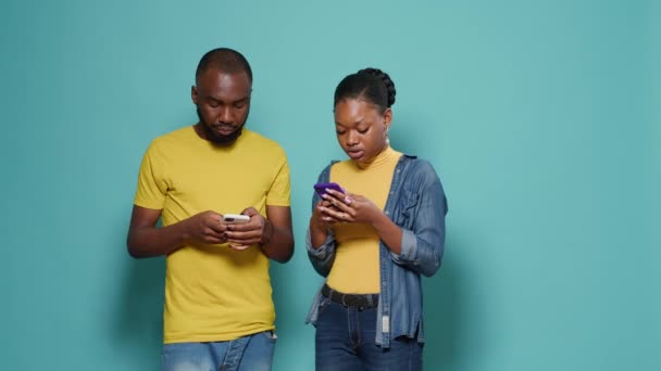 African american couple using smartphone to text messages in studio — Video Stock