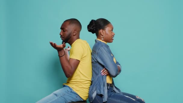 Hombre y mujer frustrados sentados espalda con espalda y discutiendo en el estudio — Vídeo de stock