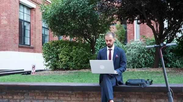 商人坐在长椅上，手持笔记本电脑浏览商业信息 — 图库照片