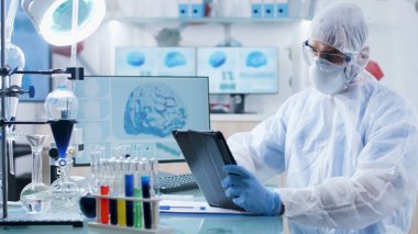 Pen ekipmanlı bir doktor elinde tablet bilgisayarla hastalıkları analiz ediyor.