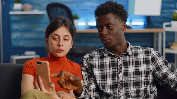 Couple interracial moderne utilisant un smartphone dans le salon — Photo