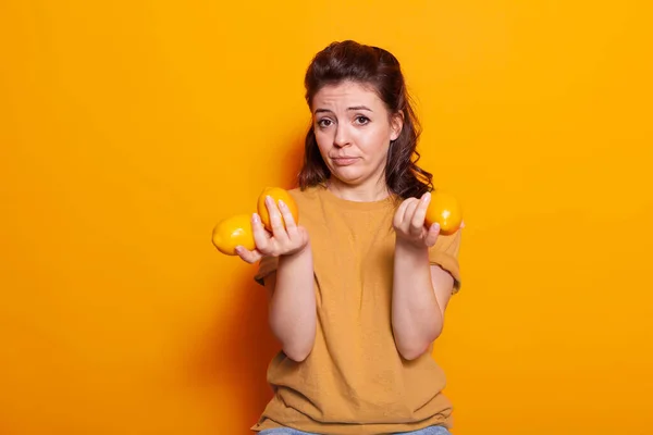 Smiling person holding yellow citrus fruits on camera in studio — Stockfoto