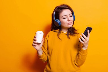 Kafkasyalı yetişkin elinde cep telefonu ve kahve tutuyor.