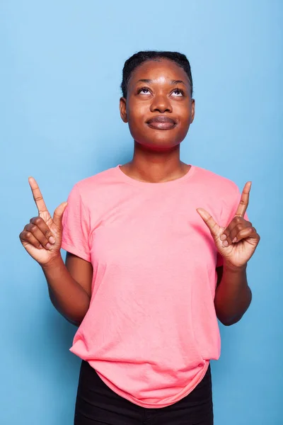 Portrait of african american teenager in pink t-shirt pointing fingers up — Stock Photo, Image