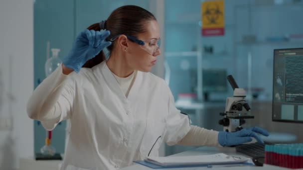 Femme scientifique regardant un échantillon de sang sur un plateau en laboratoire — Video