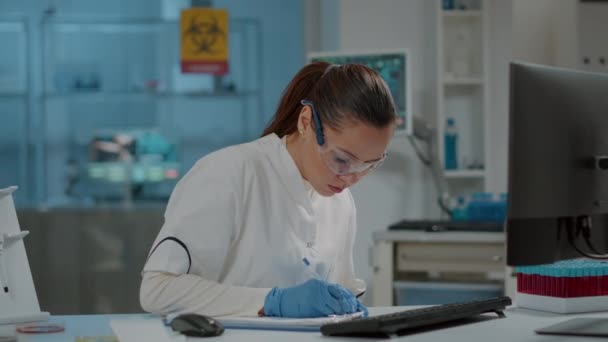 Химик-женщина делает записи для научных исследований в лаборатории — стоковое видео